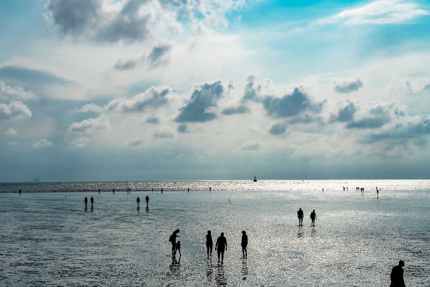 Weiter Blick auf Spaziergänger im Wattenmeer bei Büsum.