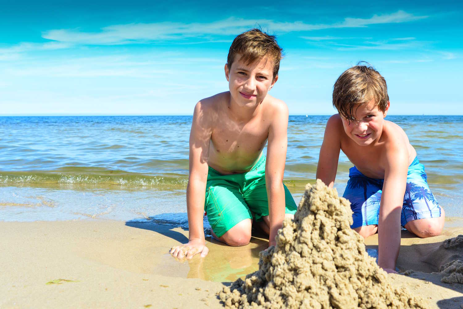 Zwei Jungs bauen eine Sandburg am Strand