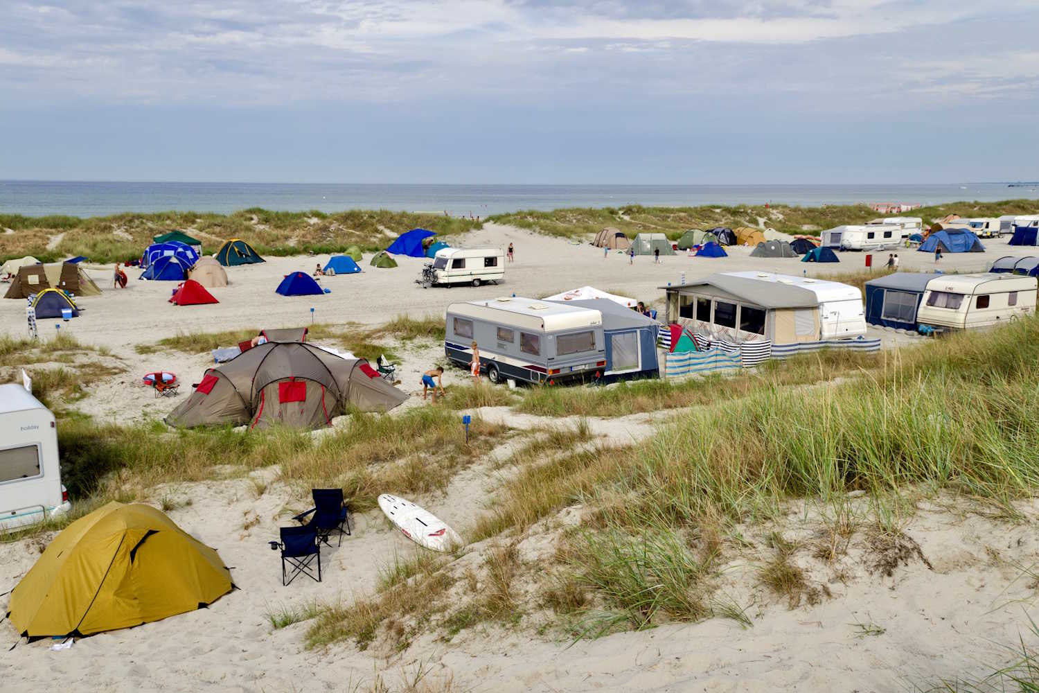 Zelte, Wohnwagen und Wohnmobile campen direkt am Strand an den Dünen.