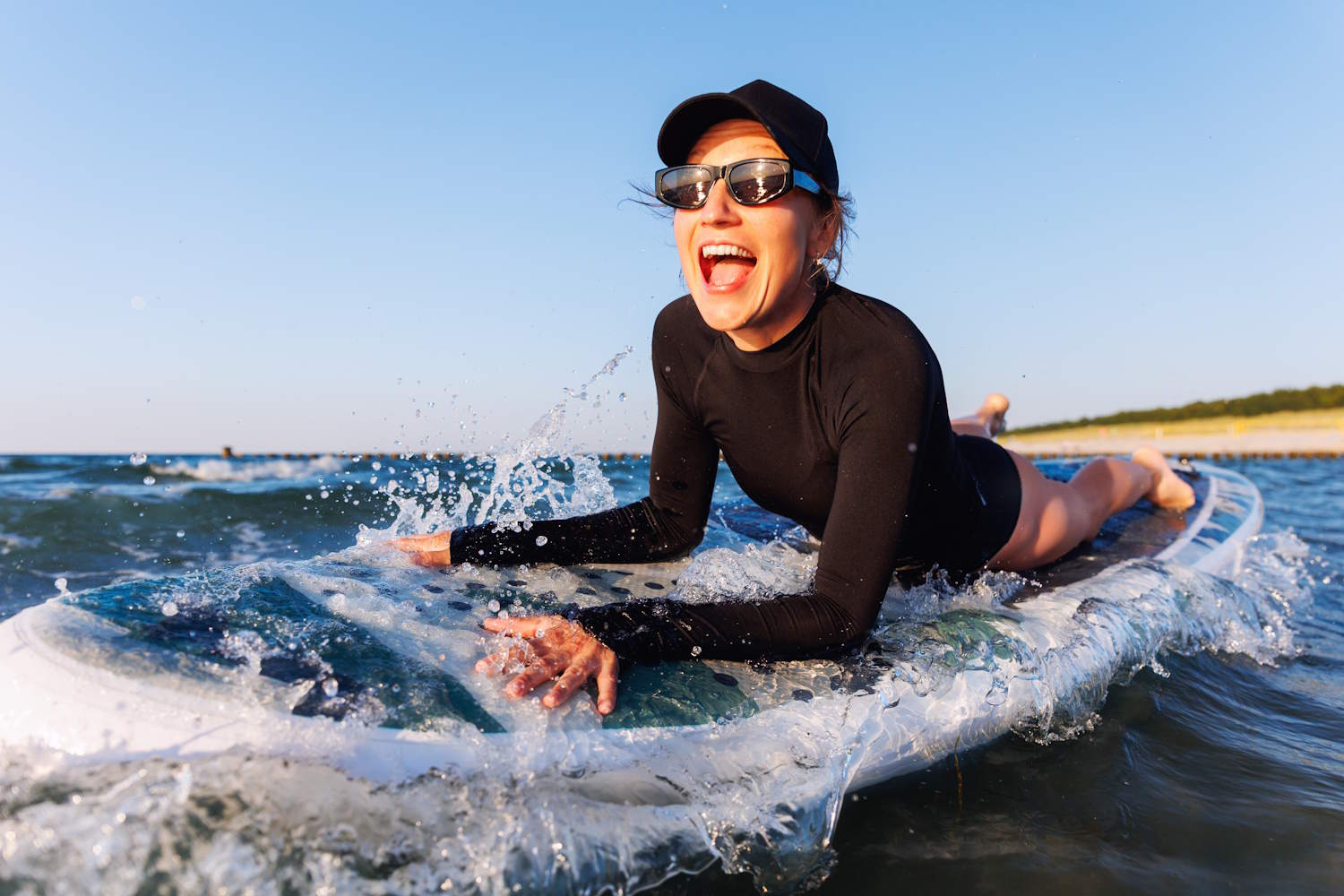 Lachende Frau auf SUP in den Wellen der Ostsee